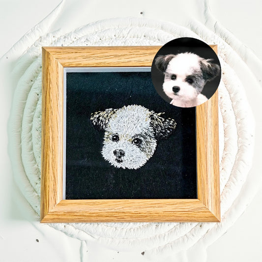 Framed needlepoint of a dog's face on a textured wall