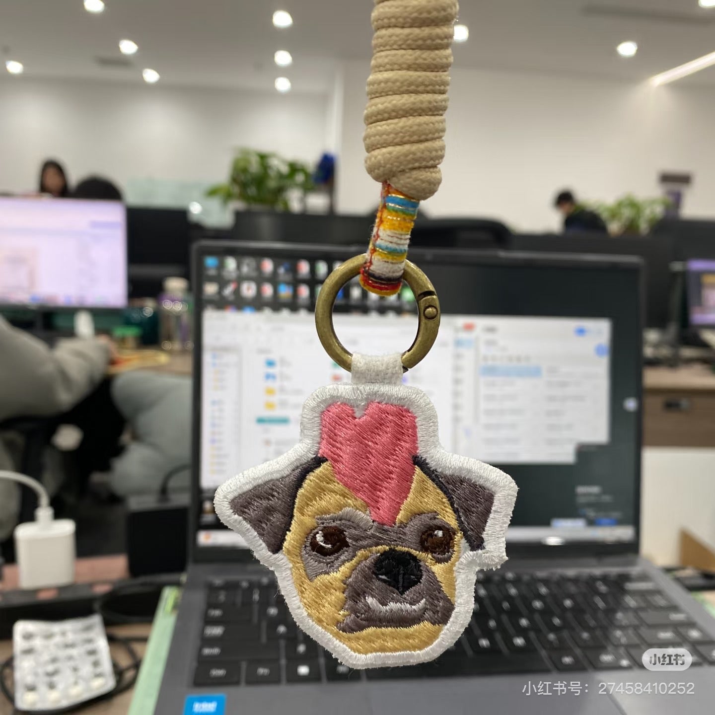 Dog-shaped keychain with a heart on a desk in an office setting